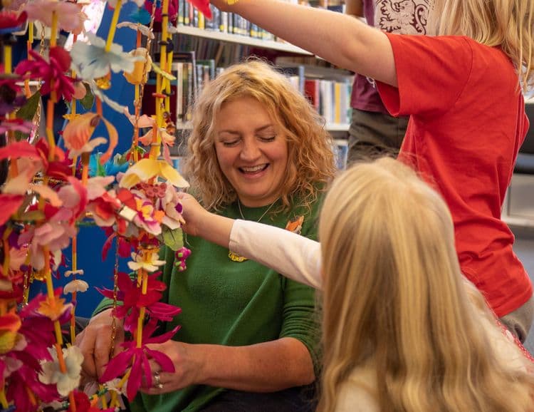 Artist Michaela McMillan doing a craft activity with children at a library.
