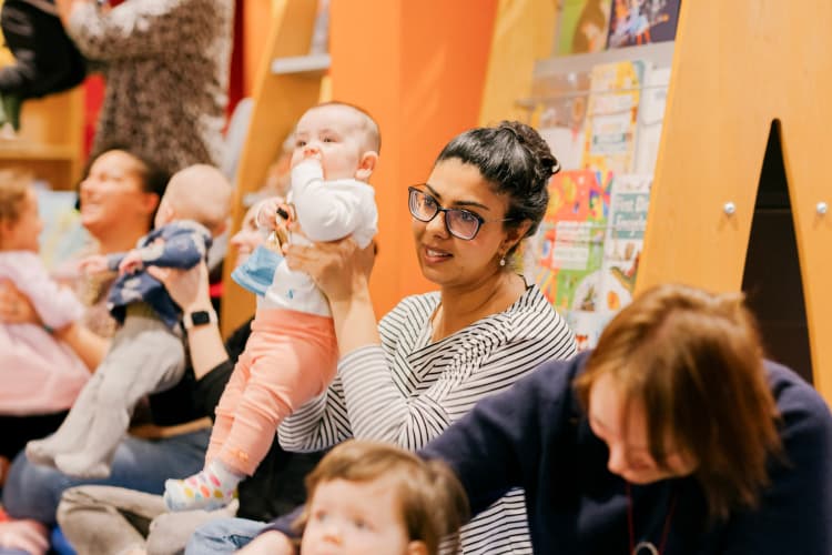 A mum holding up a toddler at a rhyme time event at the library.
