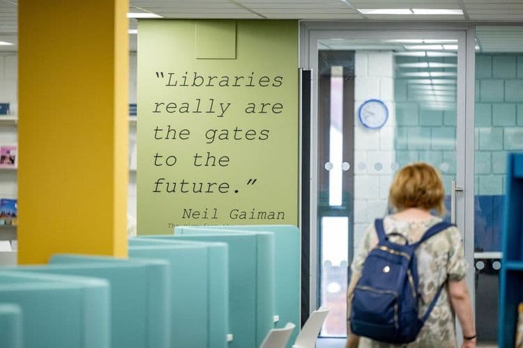 An image of a Neil Gaiman quote on the wall of a library: 'Libraries really are the gates to the future'.